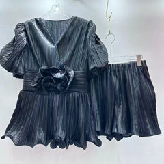 Black pleated dress with matching shorts on hangers against a white background