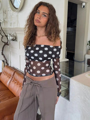 Woman wearing a polka dot top and gray pants in a living room.