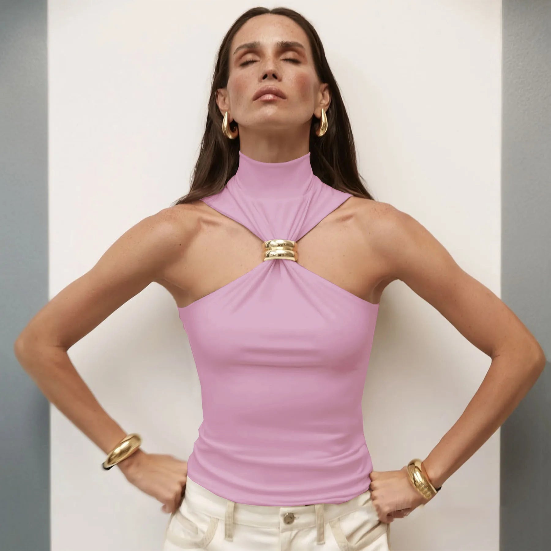 Woman wearing a pink halter top with gold accents against a neutral background