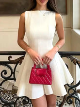 Woman in a white dress holding a pink handbag in an elegant indoor setting.