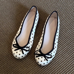 White polka dot ballet flats with black trim and a black bow