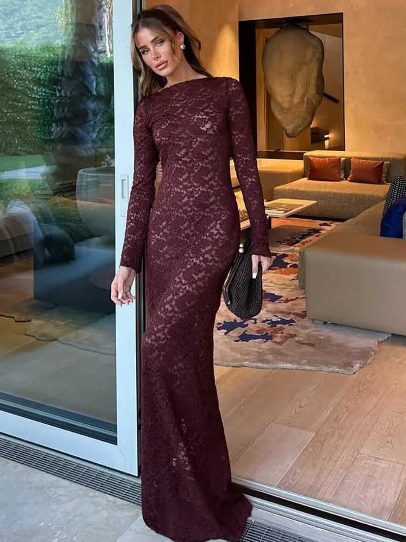 Woman in a burgundy lace dress standing in a modern living room.