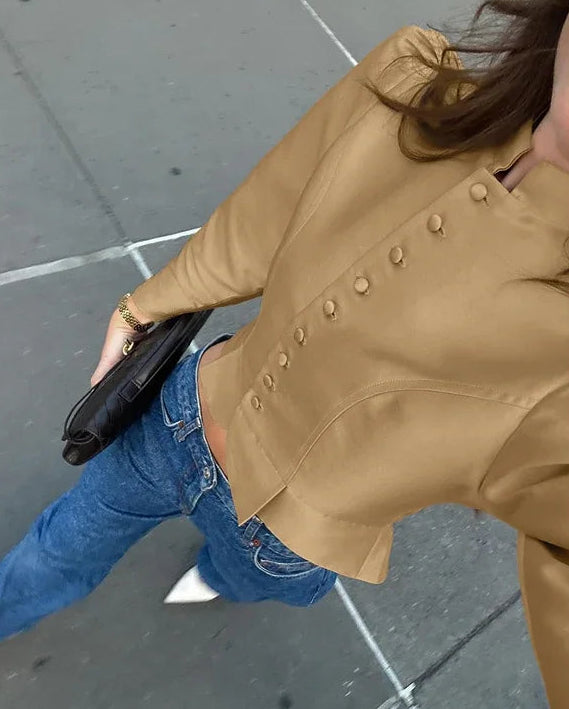 Person wearing a beige trench coat on a sidewalk