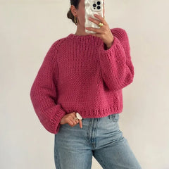 Person wearing a pink sweater and blue jeans against a plain background