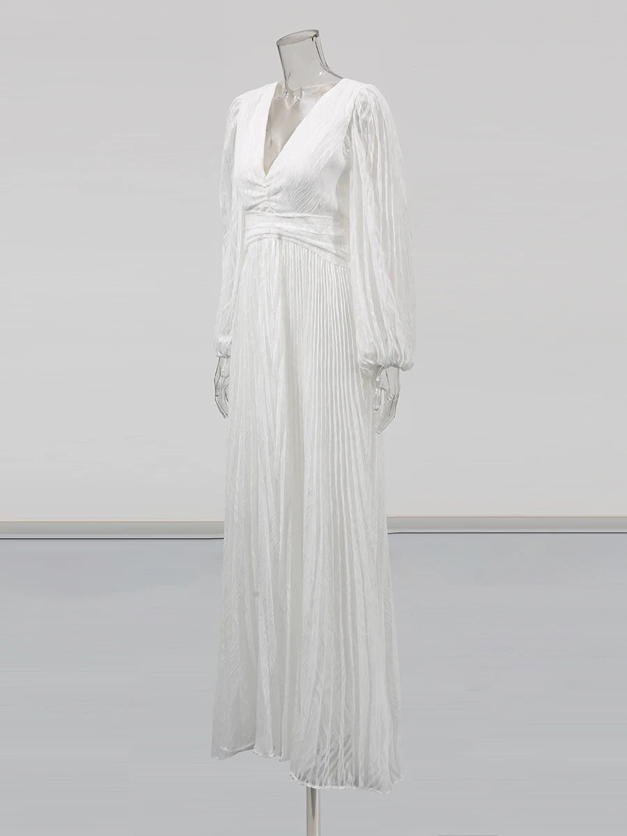White pleated dress on a mannequin against a plain background