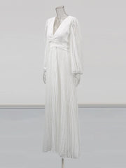 White pleated dress on a mannequin against a plain background