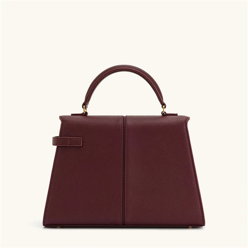 Maroon handbag with gold hardware on a white background