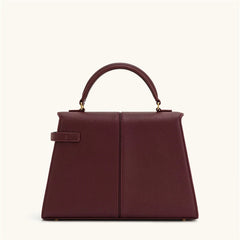 Maroon handbag with gold hardware on a white background
