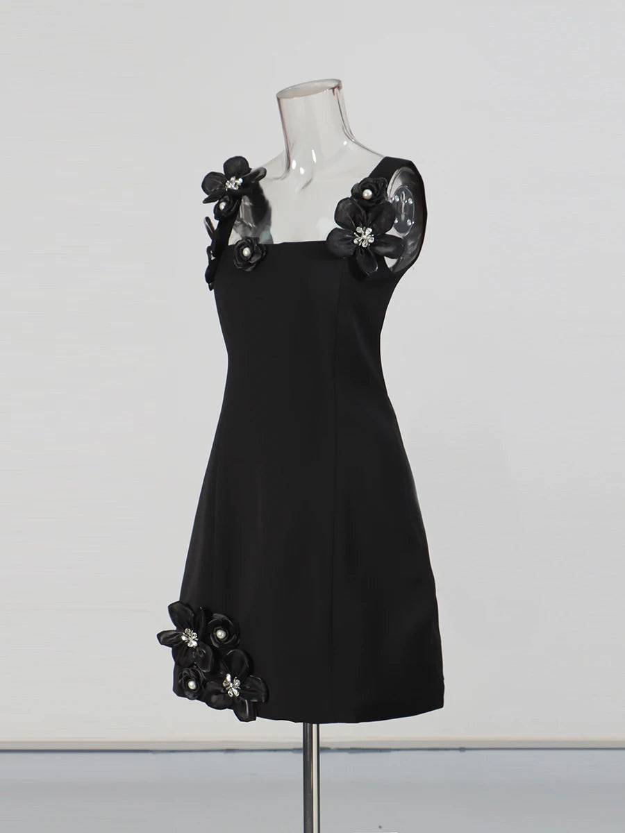 Black dress with floral embellishments on a mannequin against a white background
