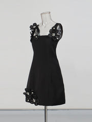 Black dress with floral embellishments on a mannequin against a white background