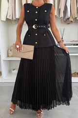 Woman wearing a black sleeveless jacket with gold buttons and a pleated black skirt, holding a beige handbag.