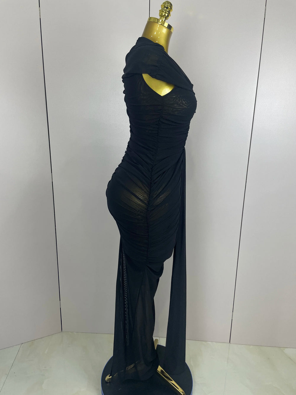 Black evening gown on a mannequin against a plain background