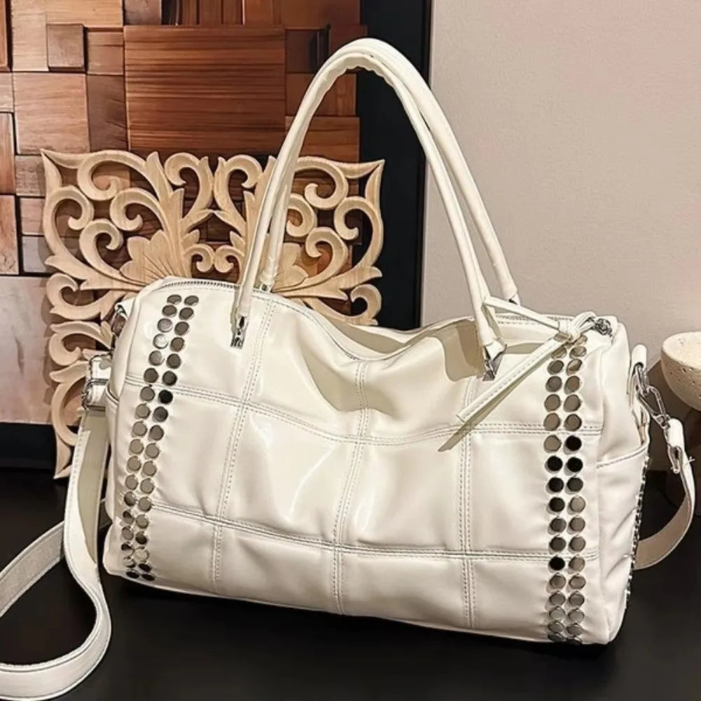 White quilted rivet tote bag on a dark surface