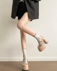 Person wearing beige platform shoes and black shorts against a plain background