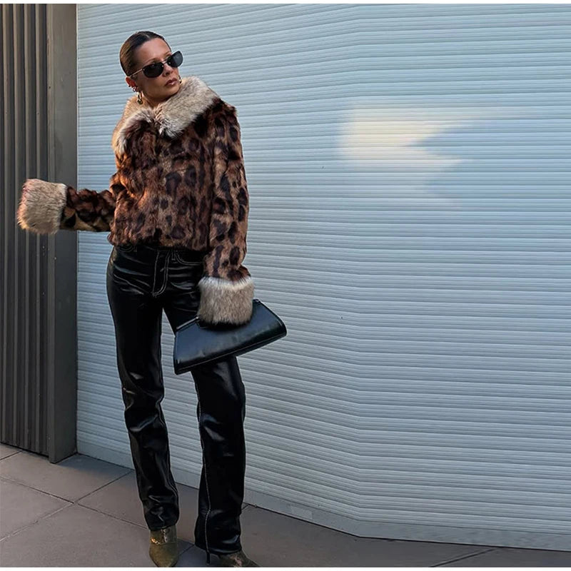 Person wearing a leopard print coat with fur trim against a light blue wall.