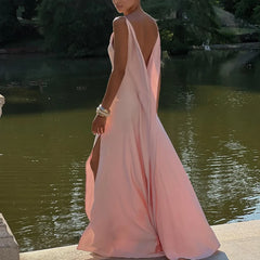 Woman in a pink dress standing by a body of water with trees in the background