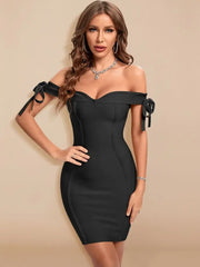 Woman wearing a black off-shoulder dress with bows on a beige background