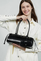 Woman holding a black handbag against a plain background