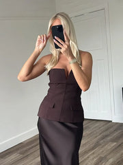 Woman taking a mirror selfie wearing a strapless brown top and skirt set.