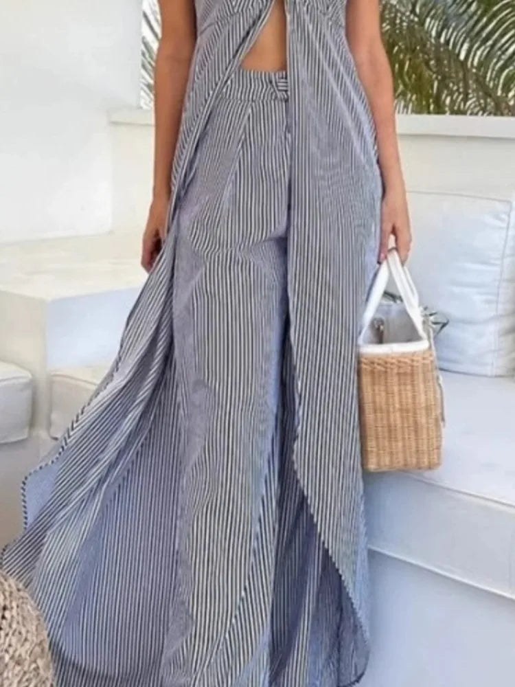 Person wearing a long, striped dress holding a woven bag on a boat.