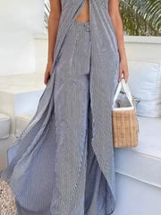 Person wearing a long, striped dress holding a woven bag on a boat.