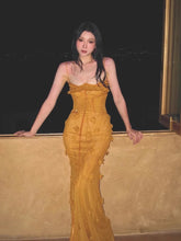 Woman in a yellow evening gown standing against a dark background