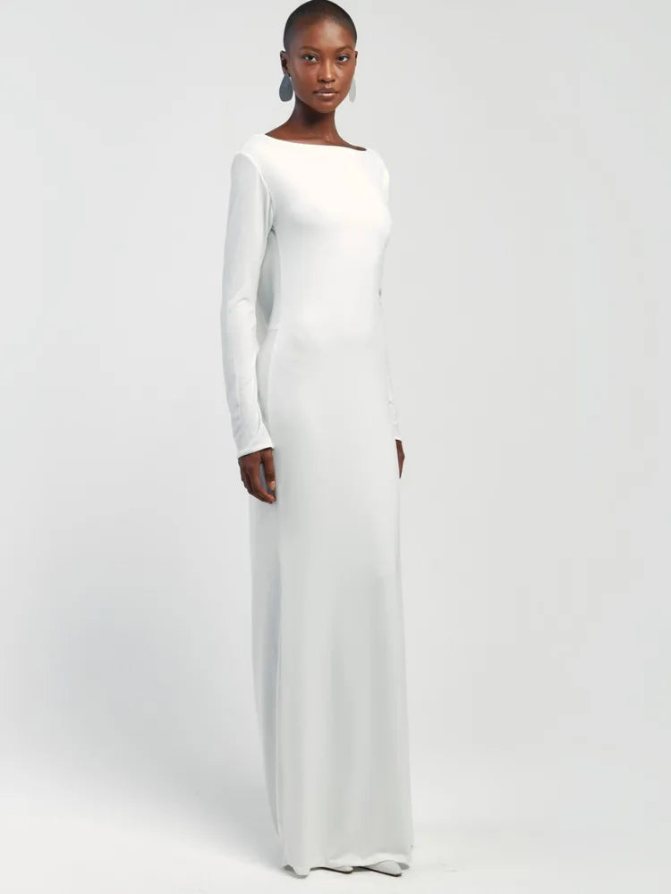 Woman wearing a long white dress against a plain background