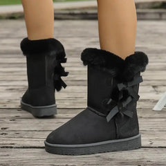 Black suede boots with fur trim on a wooden floor