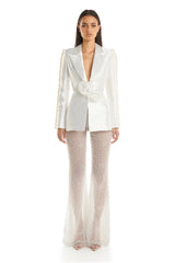 Woman wearing a white blazer with pearl details and beige pants