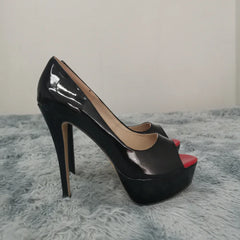 Black high-heeled platform shoes with red interior on a gray textured surface
