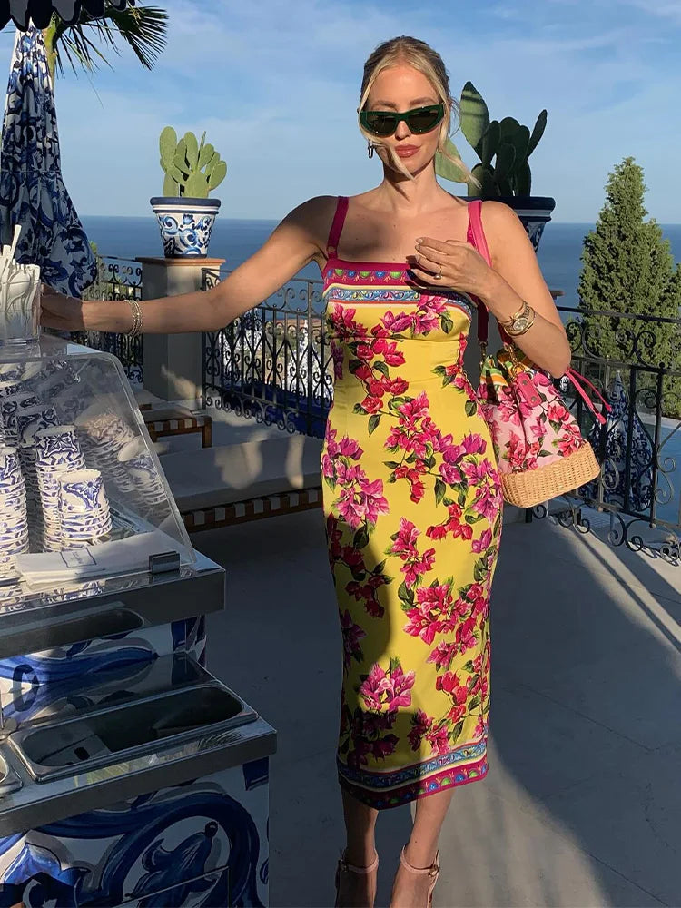Woman in a colorful dress standing on a balcony with ocean view