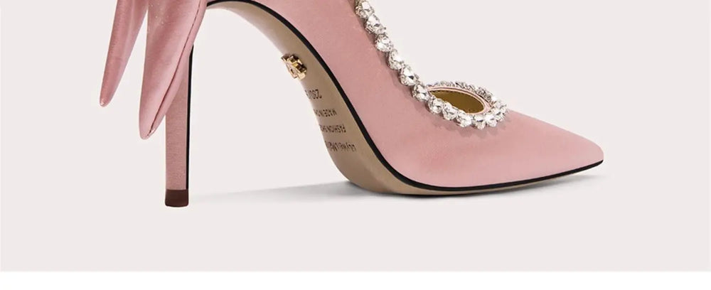 Pink high-heeled shoe with decorative embellishments on a light background