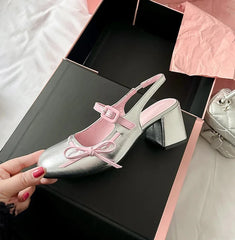 Silver patent leather chunky Mary Jane heel with pink trim and bowknot detail in a pink box.