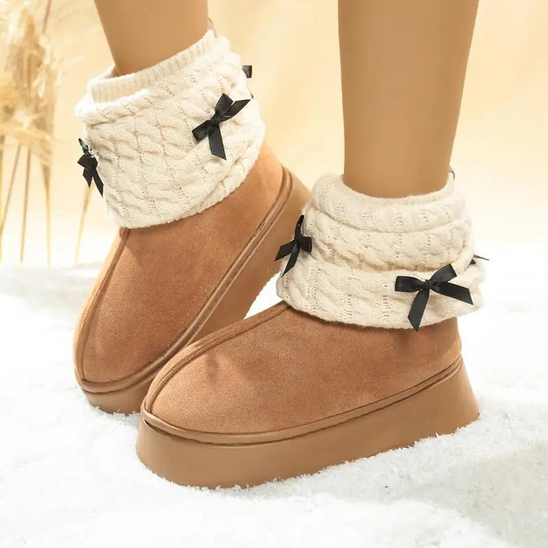 Tan slippers with white cuffs and black bows on a soft white background