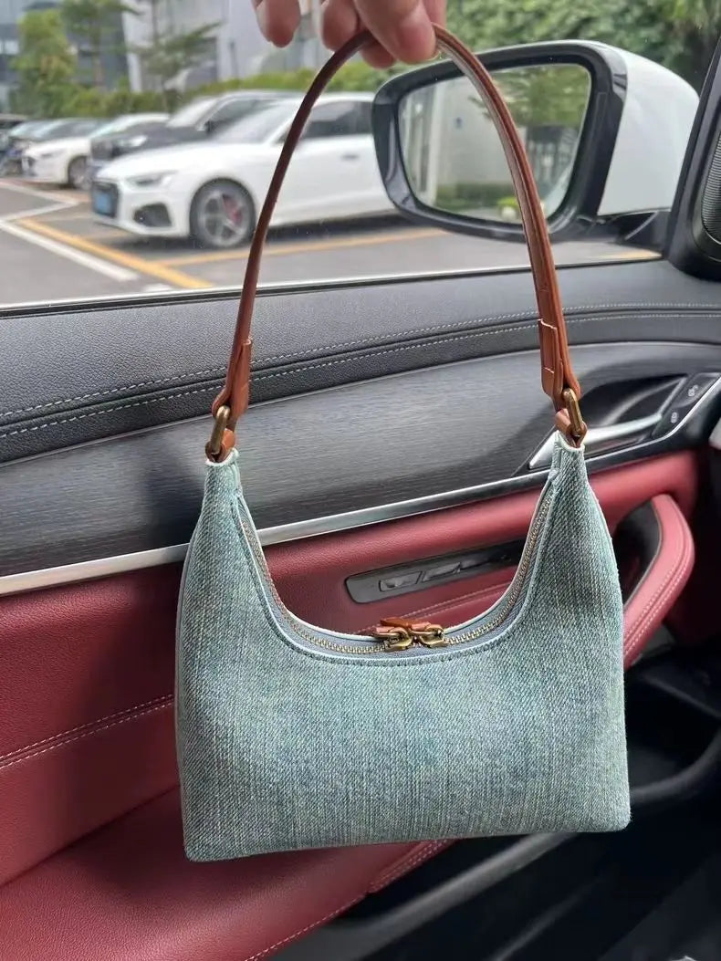 Green handbag with brown handle held by a person inside a car.