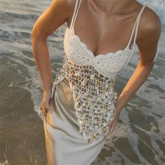 Woman wearing a white crochet top with sequin overlay on a beach.