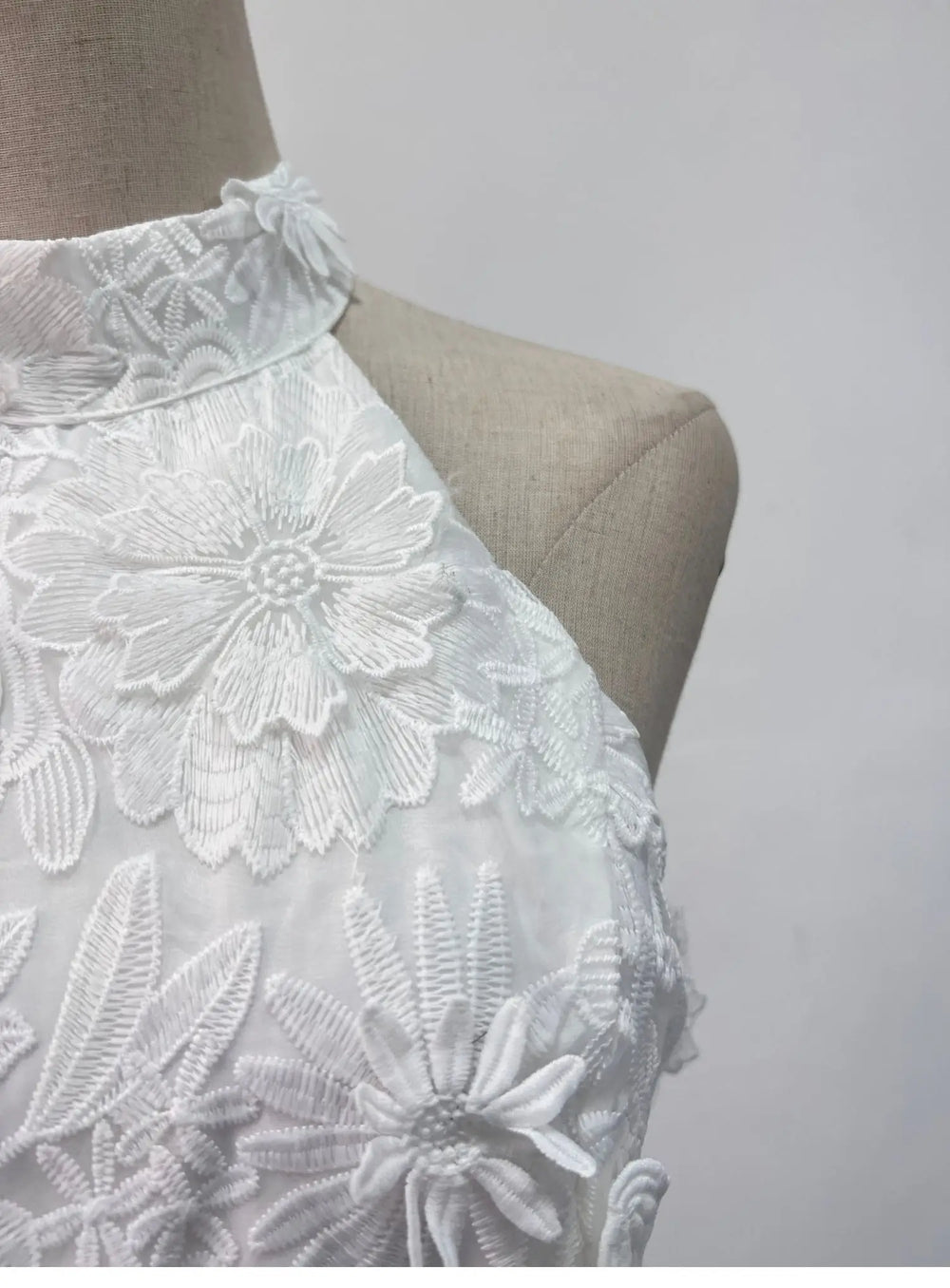 White lace top on a mannequin against a plain background
