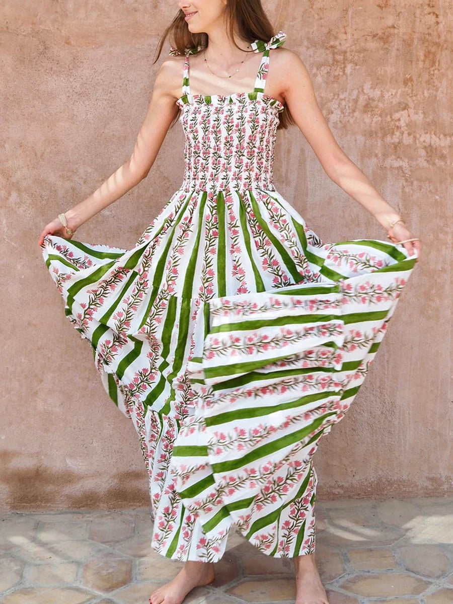 Woman wearing a floral dress with green and white pattern against a textured wall.