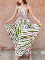 Woman wearing a floral dress with green and white pattern against a textured wall.