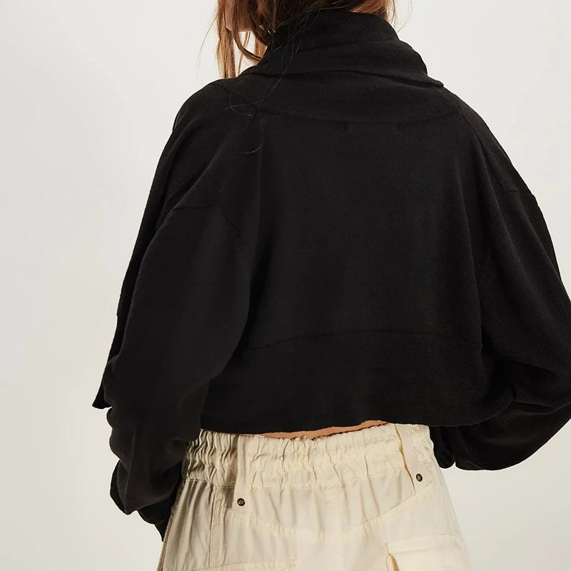 Person wearing a black jacket and beige pants on a plain background