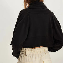 Person wearing a black jacket and beige pants on a plain background