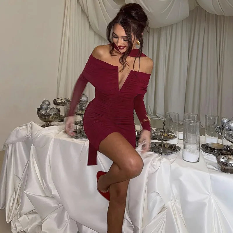 Woman in a red dress standing at a table with white tablecloth and decorative items.