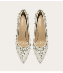 Pair of embellished white shoes on a light beige background