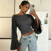Woman taking a mirror selfie wearing a black polka dot top and light blue jeans.