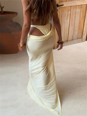 Woman wearing a long, light-colored dress with cut-out design, standing indoors.