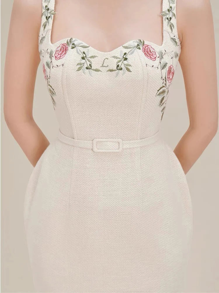 Beige dress with floral embroidery on straps against a neutral background