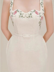 Beige dress with floral embroidery on straps against a neutral background