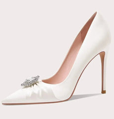 White high-heeled shoe with a decorative bow and gemstone on a light gray background