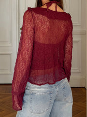 Red lace top worn by a person with light blue jeans in an indoor setting.