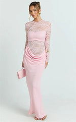 Woman wearing a pink dress with sheer long sleeves on a white background